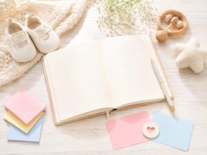 赤ちゃんの名付けや姓名判断について考える場面をイメージした、開いたノートとベビーシューズ、やさしい色のカードを並べた明るい雰囲気の画像