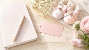 女の子の名付けで画数が変わる不安や候補名を考える場面を、名付けノートと名前候補カード、ピンクのベビーシューズで表した明るい写真